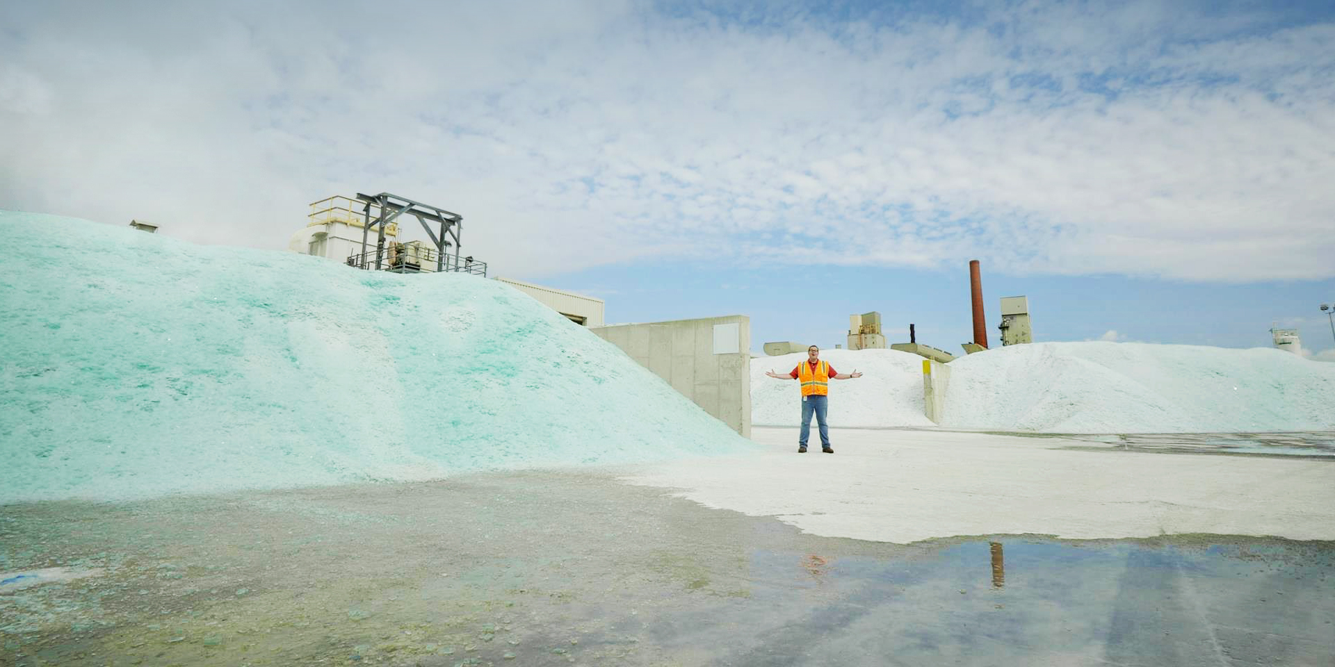 Guardian Industries employee next to a pile of broken glass waiting to be recycled